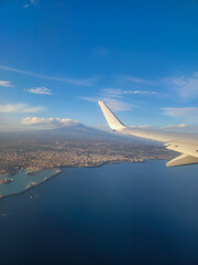 Fototapeta premium Airplane wing out of window. Vulcan, city and sea view