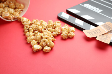 Movie clapper, sweet popcorn and tickets on red background, closeup