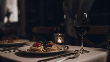 romantic dining setup featuring pasta, wine, and soft lighting creates inviting atmosphere