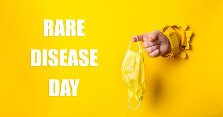 Person holding a yellow mask with the words Rare Disease Day written below
