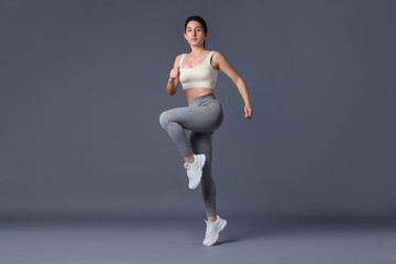 Obraz premium Woman in sportswear exercising on grey background