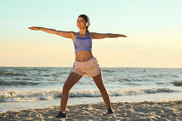 Young woman doing yoga on beach at sunset