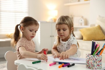 Naklejka premium Cute little sisters drawing at white table in room