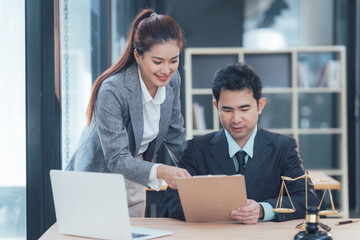 Fototapeta premium Collaborative Legal Expertise: Two professionals, a man and a woman in formal attire, engage in a focused discussion over legal documents.