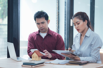 Real Estate Consultation: A focused real estate agent and client review documents and a house...