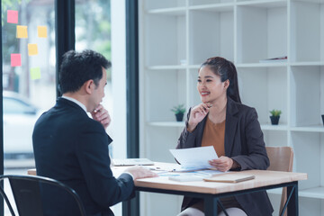 Business Meeting: A focused discussion unfolds between a man and a woman in a modern office setting.  The atmosphere is professional yet approachable.