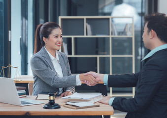 Successful Partnership: A confident businesswoman and a businessman seal a deal with a firm handshake in a modern office setting.  The image portrays trust, collaboration and mutual success. 