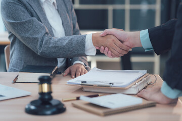 Legal Partnership: A close-up shot of two businesspeople shaking hands across a table, symbolizing a successful legal partnership.  A judge's gavel rests subtly in the foreground.