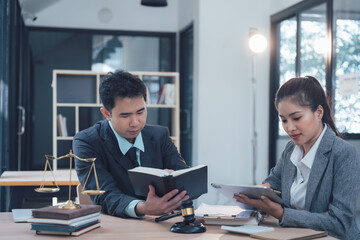 Legal Collaboration:  Two legal professionals, a male and a female lawyer, collaborate intently in their office, meticulously studying legal documents and a legal textbook.