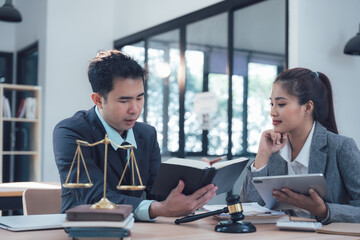 Legal Consultation: Two legal professionals in a contemporary office setting, engrossed in a detailed discussion, with scales of justice and a gavel prominently displayed.