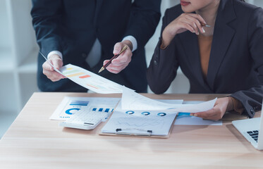 Strategic Business Review: Two business professionals collaborate closely, reviewing financial...