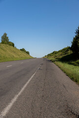 an empty straight paved road against a blue sky background