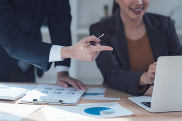 Collaborative Business Analysis: A close-up shot depicts two business professionals engaged in a collaborative discussion over financial data, one pointing to key insights on a laptop screen.