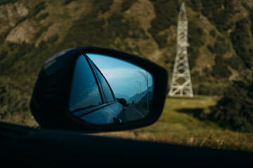 The mirror of the car and the reflected power lines and the sky