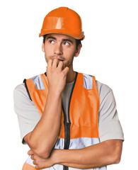 Young Hispanic worker in safety gear relaxed thinking about something looking at a copy space.