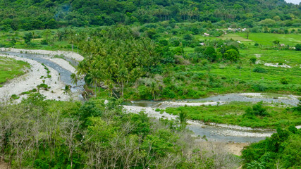 View of a green valley. View from above of a small river flowing through a valley covered with jungle. Tropical landscape.