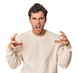 Young Hispanic man in studio screaming with rage.