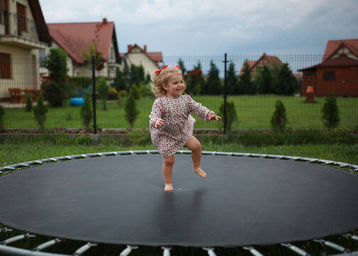 a Little child girl jumping on the trampoline in the back yard 