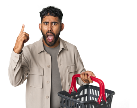 Hispanic male holding shopping basket in studio having an idea, inspiration concept. - Powered by Adobe
