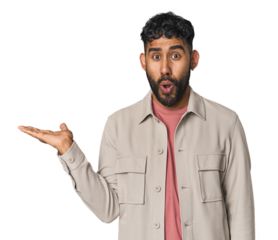 Young Hispanic man isolated impressed holding copy space on palm.