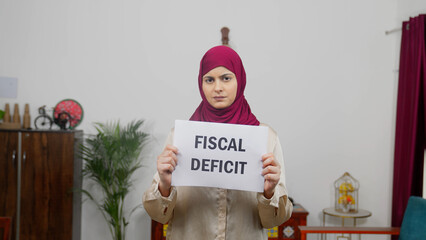 Muslim Woman in Hijab Scarf standing with Fiscal Deficit Poster