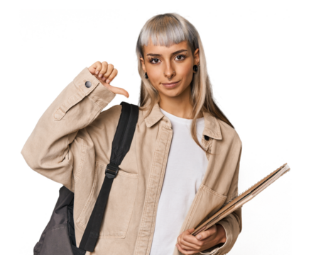Caucasian young student with books showing a dislike gesture, thumbs down. Disagreement concept.