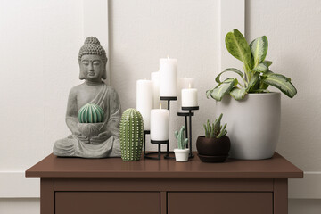 Console table in mocha mousse shade with decor and houseplants near wall. Stylish interior with trendy color of 2025 year