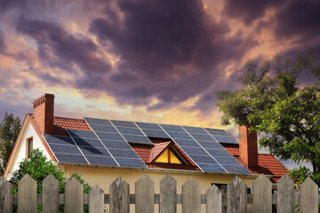 Green energy. House with solar panels on roof at sunset