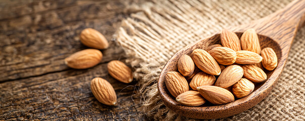 foods high in magnesium concept. Natural Almonds on Rustic Wooden Spoon Background