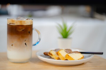Side view of ice latte coffee with butter cake in a glass on wooden table
