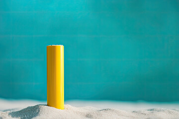 Yellow Sunscreen Tube on Sandy Beach with Bright Blue Sky Background