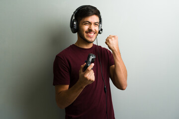 Excited gamer celebrating victory while wearing headphones and holding controller © AntonioDiaz