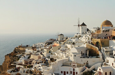 Picturesque view of the traditional white houses and windmills on the mountainside in Oia on the...