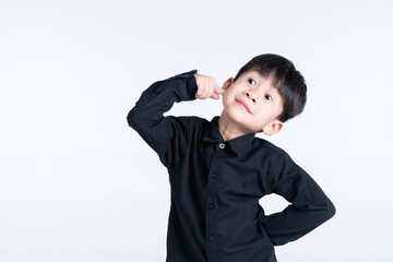 Young boy in a black shirt making a playful thinking gesture against a white background.