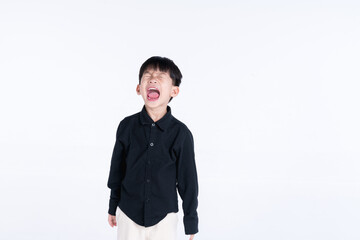 Young boy in a black shirt screaming with his mouth wide open, expressing frustration or anger against a white background.