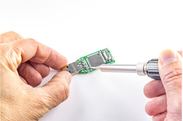 Soldering iron in the hands, repairs a damaged flash drive, on a white background