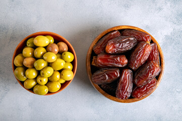 Dates fruit with a bowl of green olive on bright background 