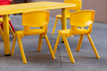 A yellow plastic kid chair sits next to another yellow plastic chair