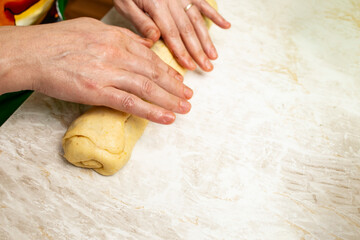 Woman hands rolling raw dough with cocoa , walnuts and turkish delight filling for cozonac making process