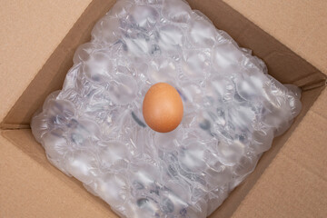 Chicken egg on air cushion bubble wrap background, insidee a cardboard box , protection concept