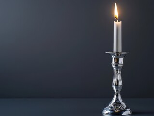 Fototapeta premium Candle with a single flame illuminating a dark background creating a serene atmosphere