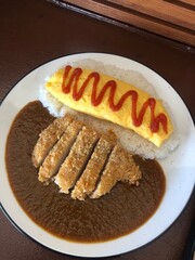 Japanese curry rice with omelet on a plate placed on the table.