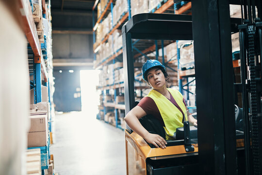Female worker operating forklift in large warehouse