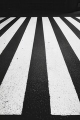 High angle view of a pedestrian crossing with black and white stripes at night. The image is in monochrome, showing the texture of the road surface