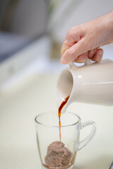 Icecream on a  table with coffee being poured into it showing the texture and refreshing look of the drink, hand holding concept.
