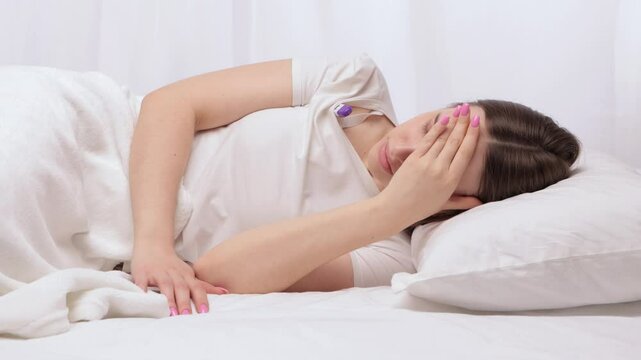 A young girl in a white bed measures her body temperature when she has the flu.