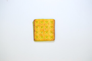 A close-up of a square biscuit with a green filling, isolated on a white background