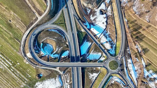 New highway interchange on Zakopianka motorway near Klikuszowa village with ramps, viaduct and traffic circle, joining the new highway with old road. Aerial view from above. Time lapse. January 2025