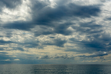 Obraz premium A huge cloudy sky filled with thick cumulus clouds creating a dramatic spectacle. Midsummer, Black Sea beach