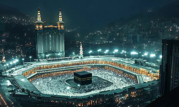A nighttime view of the Kaaba in Mecca, surrounded by worshippers and illuminated buildings.